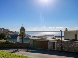 A coastal view with a stone wall and garage in the foreground and a harbor with boats in the background at Rosa in Torquay