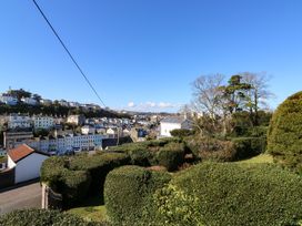 A garden with trimmed bushes and trees overlooking houses under a clear sky at Rosa in Torquay