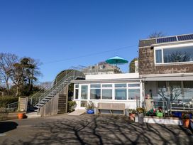 Exterior view of a building with a staircase leading to a rooftop terrace with an umbrella and various potted plants around the entrance at Rosa in Torquay