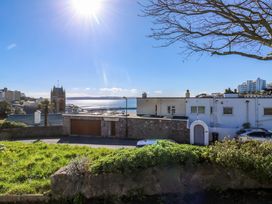 A street view with houses a church a tree and sea in the background at Rosa in Torquay