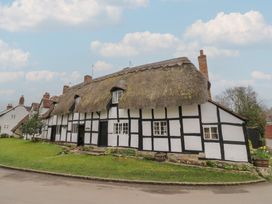 A thatched roof cottage with white walls and black timber framing beside a road at Church View in Welford-On-Avon