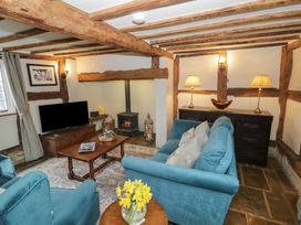 A living room with wooden beams a blue sofa two armchairs a wooden coffee table a fireplace and a television at Church View in Welford-On-Avon