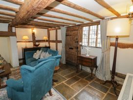 A living room with wooden beams stone floor and blue upholstered chairs at Church View in Welford-On-Avon