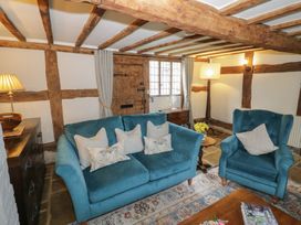 A sitting room with blue upholstered sofa and armchair wooden beams on ceiling and walls at Church View in Welford-On-Avon