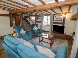 A living room with blue upholstered chairs and sofa a wooden coffee table and a television at Church View in Welford-On-Avon