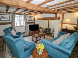 A living room with blue armchairs and sofa a wooden coffee table a fireplace and a TV at Church View in Welford-On-Avon