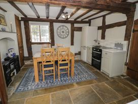 A kitchen dining area with wooden beams a wooden table and chairs a rug a refrigerator oven and cabinets at Church View in Welford-On-Avon