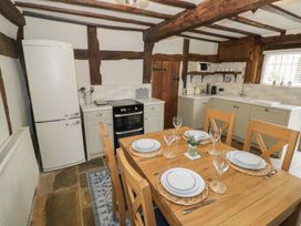 A kitchen with wooden dining table set for four and appliances at Church View in Welford-On-Avon