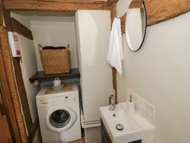 A utility room with a washing machine sink mirror and basket at Church View in Welford-On-Avon