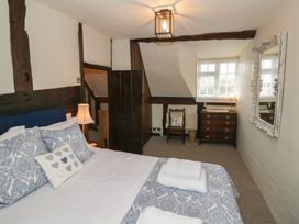 A bedroom with a bed a lamp a chair a chest of drawers and a mirror at Church View in Welford-On-Avon