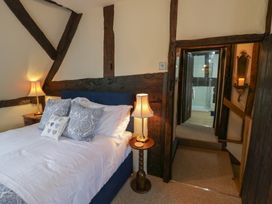 A bedroom with a bed and bedside lamps and a doorway leading to a bathroom at Church View in Welford-On-Avon