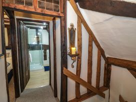 A hallway with wooden beams and a candle holder on the wall leading to a bathroom with a glass shower at Church View in Welford-On-Avon