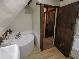 A bathroom with a bathtub sink wooden door and towel rail at Church View in Welford-On-Avon