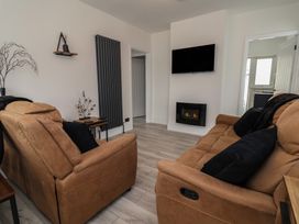 A living room with sofas and a television at Driftwood in Rhyl