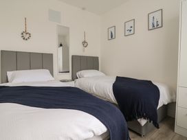 A bedroom with two beds and a mirror at Driftwood in Rhyl