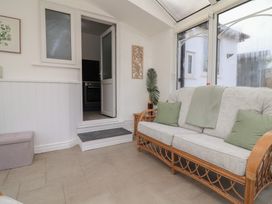 A conservatory with a couch and door leading to a kitchen at Driftwood in Rhyl