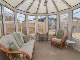 A conservatory with seating and a table at Driftwood in Rhyl