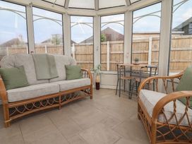 A conservatory with a sofa and a table at Driftwood in Rhyl