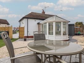 A garden with a table and chairs near a conservatory at Driftwood in Rhyl