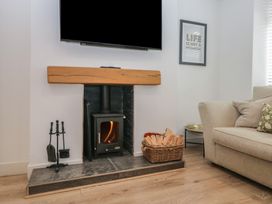 A living room with a stove and firewood at Highfield Cottage in Windermere
