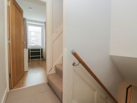 A hallway with a staircase and door at Highfield Cottage in Windermere