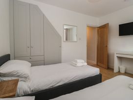 A bedroom with two beds and a wardrobe at Highfield Cottage in Windermere