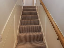 A staircase with carpet and handrail at Highfield Cottage in Windermere
