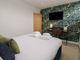 A bedroom with a bed, desk, and television at Highfield Cottage in Windermere