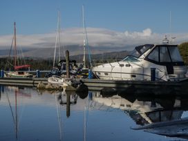 A dock with boats and mountains visible near the water at Highfield Cottage in Windermere
