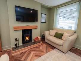 A living room with a television and fireplace at Highfield Cottage in Windermere