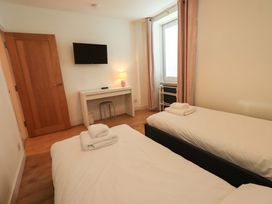 A bedroom with two beds and a desk at Highfield Cottage in Windermere