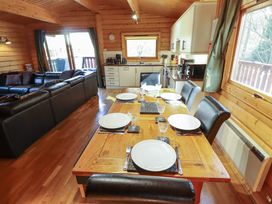 A dining table set with plates and glasses in a wooden kitchen and living room at Forest Lodge in Kenwick Woods