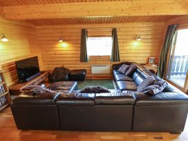 A living room with a black leather sectional sofa a television a bean bag and wooden walls at Forest Lodge in Kenwick Woods