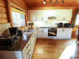 A kitchen with white cabinets dark countertops appliances and wooden walls and ceiling at Forest Lodge in Kenwick Woods