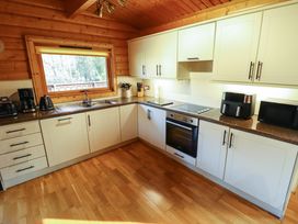A kitchen with white cabinets and wooden walls and floor at Forest Lodge in Kenwick Woods