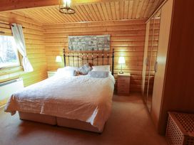 A bedroom with a double bed two bedside tables lamps a wardrobe and a window at Forest Lodge in Kenwick Woods