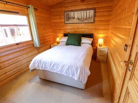 A bedroom with a bed white bedding bedside tables with lamps and a window at Forest Lodge in Kenwick Woods