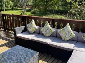 An outdoor seating area with a sofa and cushions at Forest Lodge in Kenwick Woods