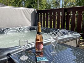 An outdoor area with a hot tub and champagne at Forest Lodge in Kenwick Woods