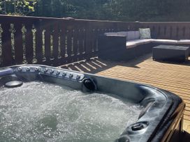 A hot tub and seating area on a deck at Forest Lodge in Kenwick Woods
