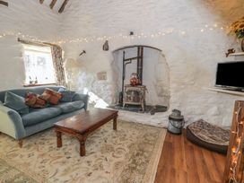 A living room with a sofa coffee table wood stove and television at Old Ty'n Y Wern Rhosygwalia near Bala