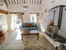 A living room with a blue sofa cushions wooden coffee table wood stove and floral curtains at Old Ty'n Y Wern in Rhosygwalia near Bala