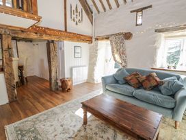 A living room with blue sofa wooden coffee table floral curtains and exposed wooden beams at Old Ty n Y Wern in Rhosygwalia near Bala