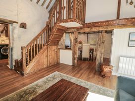 A wooden staircase with fairy lights leading upstairs in a room with wooden beams a dining area with white chairs and a wooden table at Old Ty'n Y Wern in Rhosygwalia near Bala