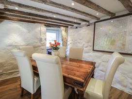 A dining room with a wooden table six cream chairs flowers in a vase and a large framed map on the wall at Old Ty'n Y Wern in Rhosygwalia near Bala