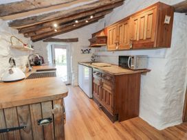 A kitchen with wooden cabinets a microwave a kettle and a door at Old Ty'n Y Wern in Rhosygwalia near Bala
