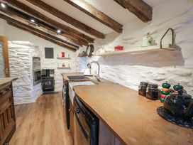 A kitchen with wooden countertops a wood stove and exposed wooden beams at Old Ty'n Y Wern in Rhosygwalia near Bala