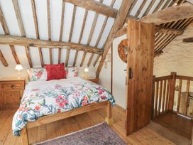 A bedroom with a floral bedspread wooden beams wooden floor and a wooden door at Old Ty'n Y Wern in Rhosygwalia near Bala