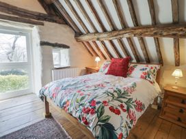 A bedroom with wooden beams and floral bedding at Old Ty'n Y Wern in Rhosygwalia near Bala
