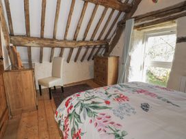 A bedroom with wooden beams floral bedding a chair wooden furniture and a glass door at Old Tyn Y Wern in Rhosygwalia near Bala